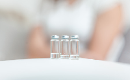 Ampules with medicines standing on table against sitting patientの写真素材