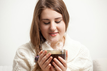 Portrait of brunette woman looking at vaporing tea cupの写真素材