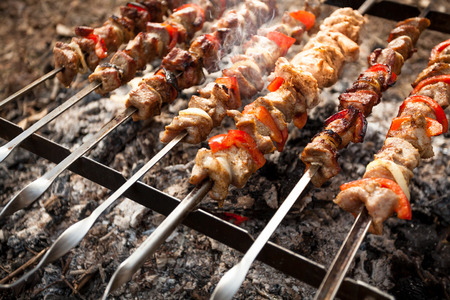 Photo of kebab on metal skewers grilling on fireの写真素材