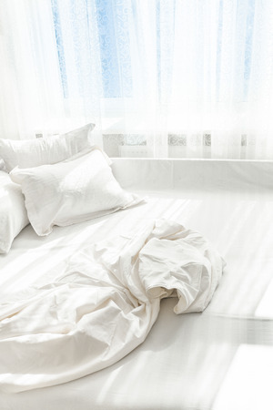 Photo of unmade bed against windowの写真素材