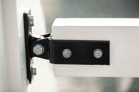 Closeup photo of metal clamp fixing two white wooden boards on bridgeの写真素材