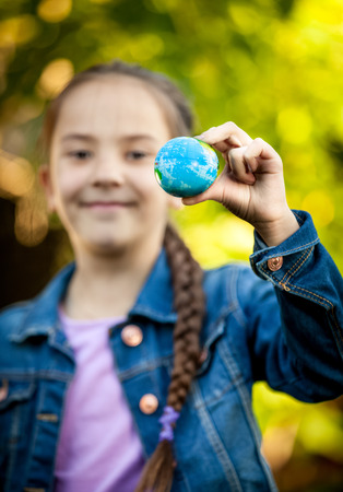 Closeup shot of smiling girl holding little Earth at handの写真素材