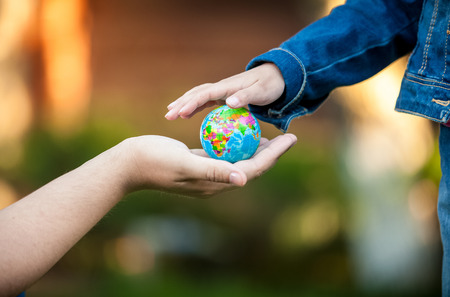Closeup shot of man giving little girl globe on handの写真素材