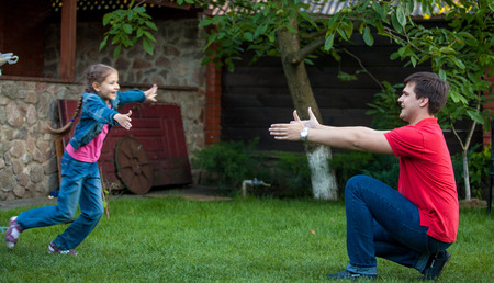 Happy daughter running at father to hug him at parkの写真素材
