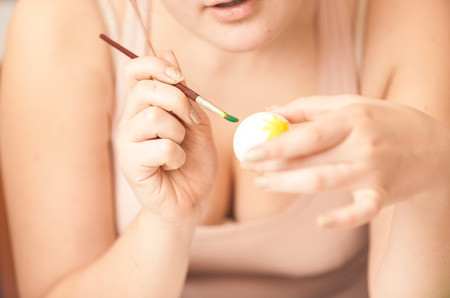 Closeup portrait of sexy woman painting white easter eggの写真素材