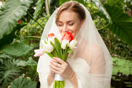 Closeup portrait of beautiful bride smelling bridal bouquetの写真素材