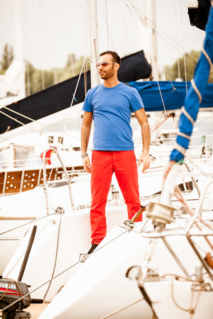 Handsome stylish macho standing on white yachtの写真素材