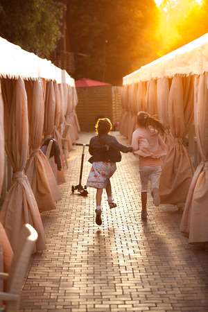 Two little girls running on street at sunsetの写真素材