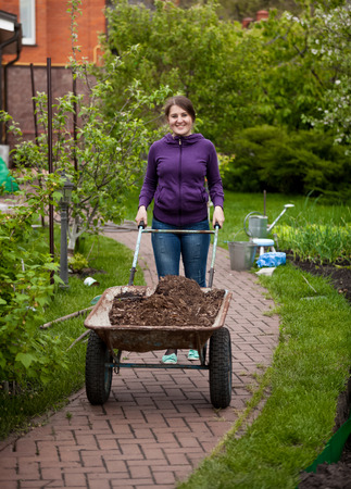Beautiful smiling woman carrying garden wheelbarrowの写真素材