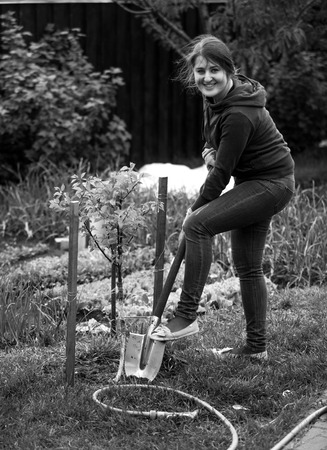 Black and white photo of woman working on garden bed with shovel
