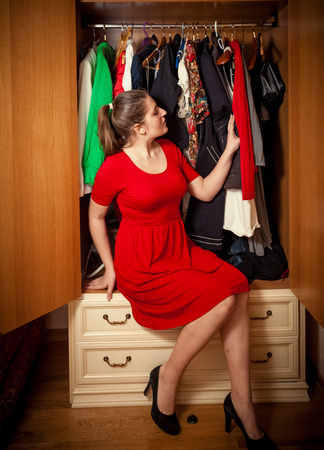 Beautiful sexy woman choosing what clothes to wear at wardrobeの写真素材