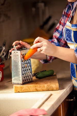 Closeup photo of woman grating carrot on wooden boardの写真素材