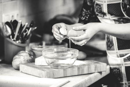 Black and white closeup photo of woman cracking eggの写真素材