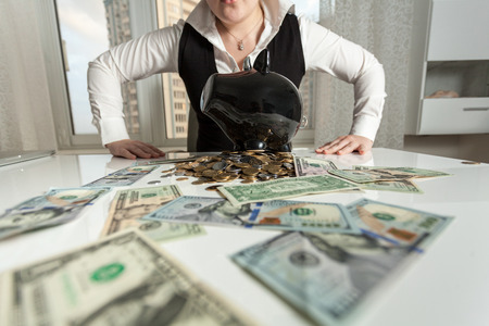 Closeup photo of businesswoman sitting behind table with piggy bankの写真素材