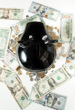 Closeup photo of black piggy bank on dollar banknotesの写真素材