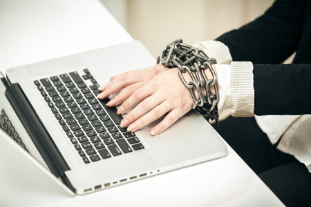 Closeup photo of female hand chained up to laptopの写真素材