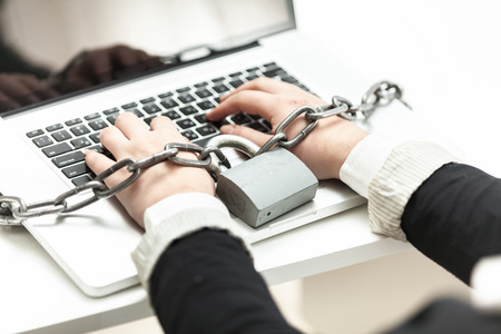 Closeup photo of woman locked in chain typing on laptopの写真素材