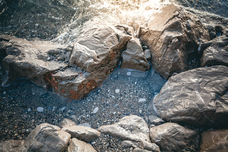Closeup photo of gray rocks at sea shore at sunsetの写真素材