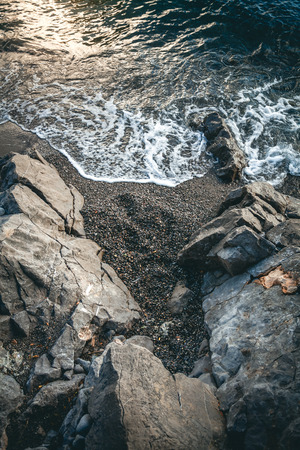 Beautiful view of sea wave covering cliffs at sunsetの写真素材