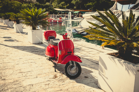 Toned photo of retro red scooter parked at sea portの写真素材