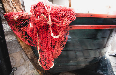 Closeup shot of red fishnet lying blue wooden rowboatの写真素材