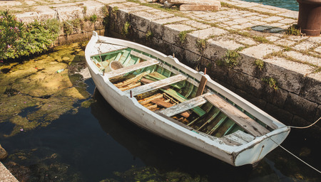 Old wooden rowboat mooring to ancient stone berthの写真素材
