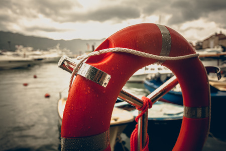 Toned photo of red lifebuoy at rainy weather in seaportの写真素材