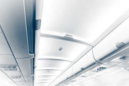 Toned photo of long ceiling in airplane with exit signの写真素材