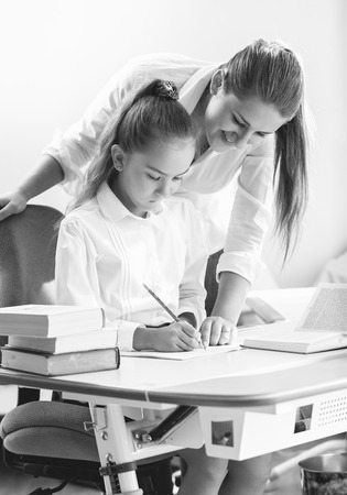 Black and white portrait of mother doing homework with daughterの写真素材