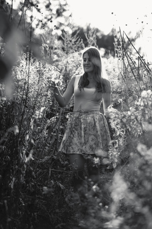 Black and white photo of beautiful cute woman walking at meadow at sunny dayの写真素材