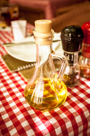 Closeup photo of glass bottle of olive oil on table at restaurantの写真素材