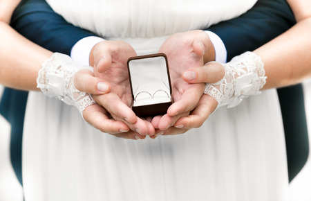 Closeup photo of bride and groom holding open box with wedding ringsの写真素材