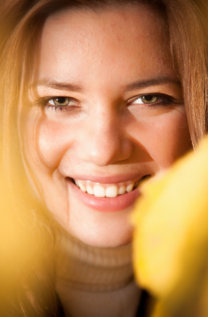 Closeup portrait of beautiful redhead woman smiling in yellow leavesの写真素材