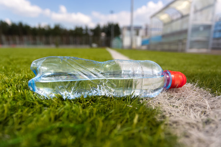 Closeup shot of plastic bottle of water lying on grass soccer fieldの写真素材