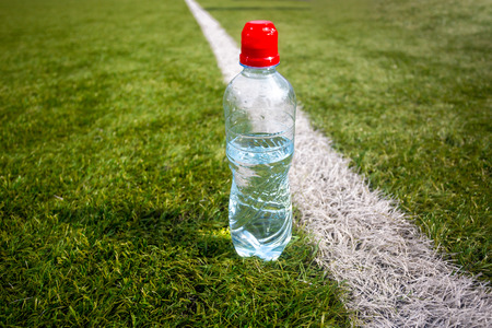 Photo of plastic bottle of water on green grass at football fieldの写真素材