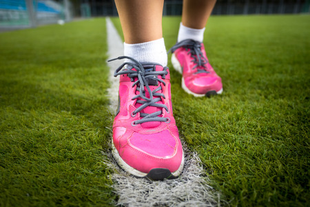 Closeup shot of woman in pink sneakers running on fresh grass