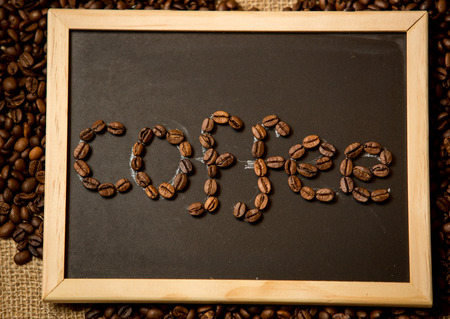 Closeup photo of word "coffee" written by coffee beans on black chalk boardの写真素材