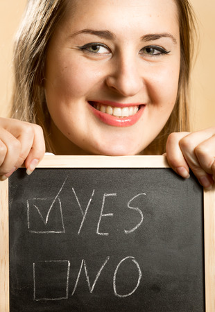 Closeup portrait of smiling woman holding board with two answersの写真素材