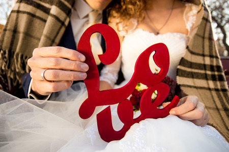 Closeup photo of young bride and groom holding Love sign in handsの写真素材