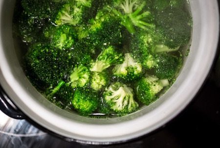 Closeup photo of broccoli boiling in white metal panの写真素材