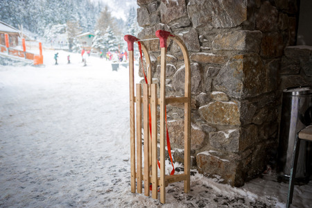 Closeup photo of vintage wooden sleighs on street next to stone wallの写真素材