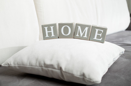 Closeup photo of word Home spelled on wooden blocks lying on sofaの写真素材