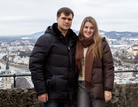 Portrait of beautiful smiling couple posing against cityscape at cold dayの写真素材