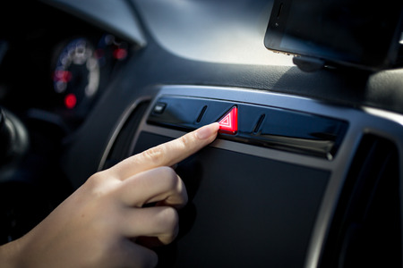 Young woman pressing emergency button on car dashboardの写真素材