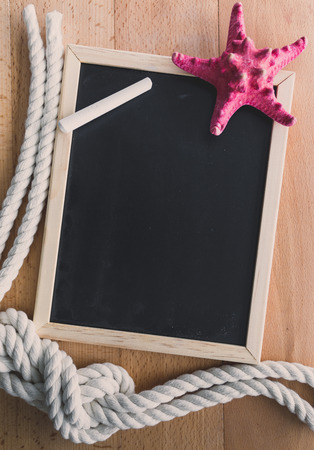 Vertical blackboard decorated by ropes and red starfishの写真素材