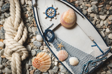 Wooden frame decorated by shells and ropes lying on stones at shore