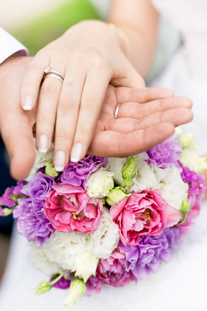Closeup soft focus photo of groom holding brides hand on bridal bouquetの写真素材