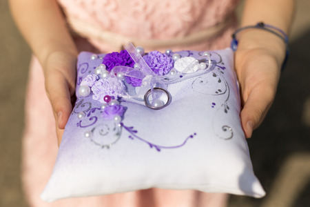 Closeup shot of little girl holding cushion with wedding ringsの写真素材