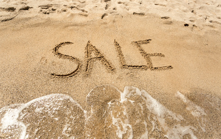 Conceptual shot of Sale written on sandy beachの写真素材