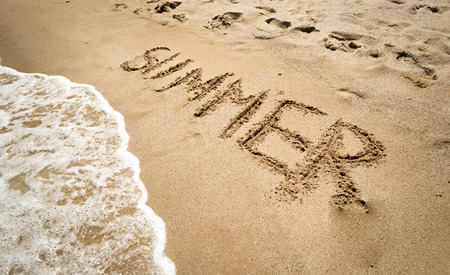 Conceptual photo of word "Summer" written on sand being washed off by waveの写真素材